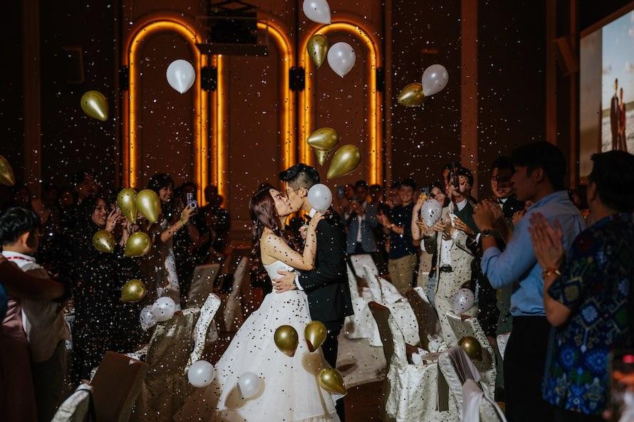 couple kissing during march in with confettis and balloons